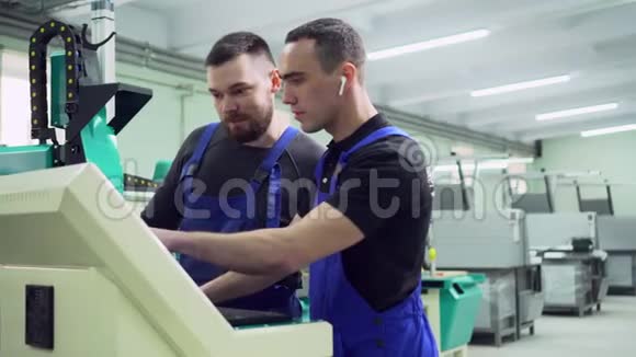 两名工厂工人正在机器附近讨论视频的预览图