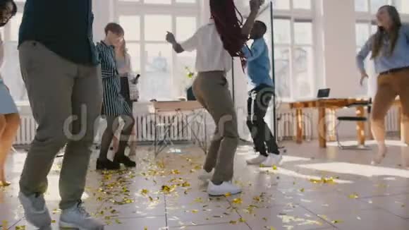兴奋的多民族商务人士庆祝团队成功在有趣的办公室聚会上跳舞地板上的纸屑慢动作视频的预览图