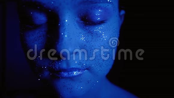 闪闪发光的艺术化妆女人闪闪发光的脸蓝色的光芒视频的预览图