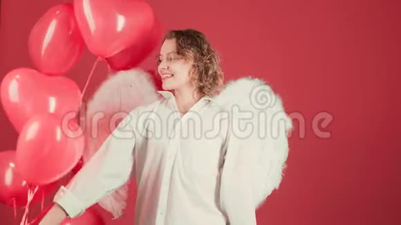 有趣的天使女人手里拿着一个红色的气球快乐的模特玩得开心用红色庆祝视频的预览图