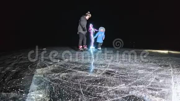 家人是滑冰之夜女孩和男孩在大自然中骑花样冰鞋母亲女儿和儿子视频的预览图