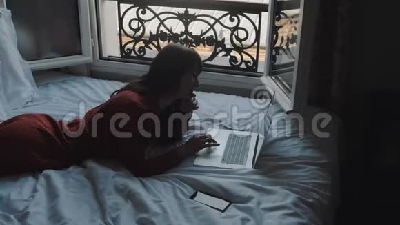 高角度快乐的白种人作家在法国阳台床上的笔记本电脑上打字找到了创造性的灵感慢动作视频的预览图
