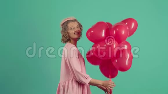 假日派对情人节美女带着红色气球笑绿色背景美丽快乐的年轻女子视频的预览图