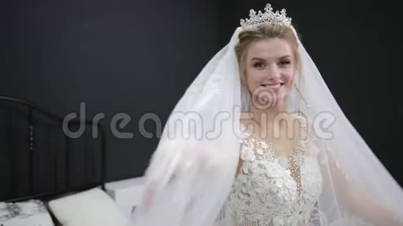 年轻的新娘穿着白色婚纱玩着面纱拍着微笑的相机视频的预览图