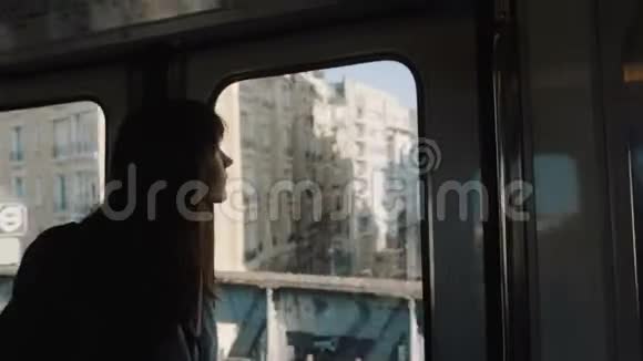 巴黎地铁列车上年轻快乐的美丽旅游妇女透过窗户缓慢地看着城市建筑视频的预览图