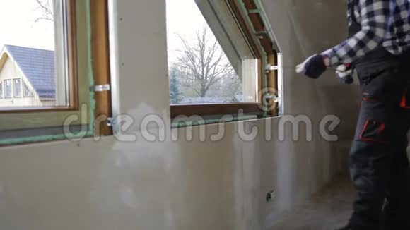 汉德曼建筑工人在一个新的绝缘和填充干燥的墙壁阁楼安装PVC窗户视频的预览图