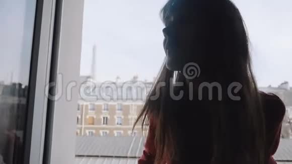 快乐美丽年轻时尚的女性博主在房间窗口摆姿势享受令人惊叹的埃菲尔铁塔观景慢动作视频的预览图