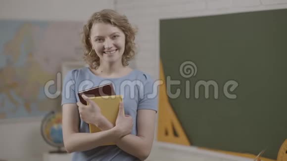 女学生或女教师在教室里拿书准备上学了微笑女讲师视频的预览图