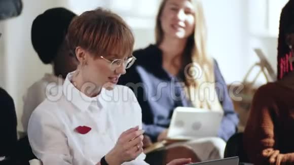 快乐的年轻聪明的高加索商务女性在现代办公会议期间的公司研讨会上提问视频的预览图