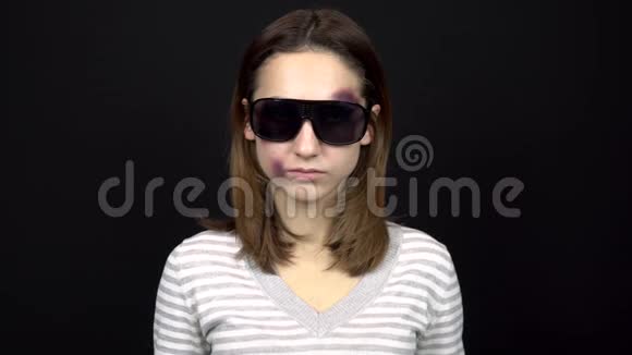 一位年轻女子摘下太阳镜露出脸上的瘀伤一个脸上有瘀伤的女人年轻时的争吵视频的预览图