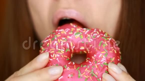 贴身女人吃一个粉红色的甜甜圈好吃甜甜的牙齿饮食节食女性口咬甜点视频的预览图
