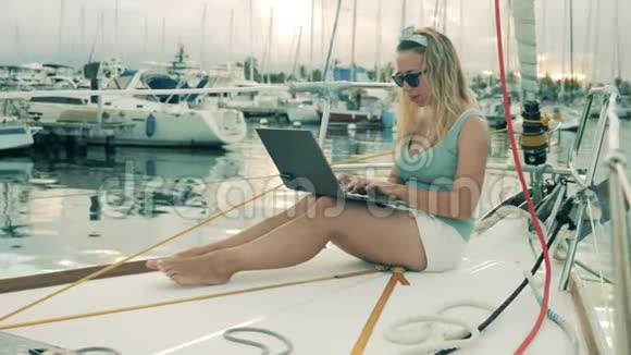 在码头坐游艇的时候女孩喜欢用笔记本电脑视频的预览图