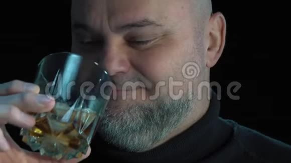 有感情的胡子男人喝威士忌加冰块孤立于黑色背景特写肖像酒精饮料和酒精视频的预览图