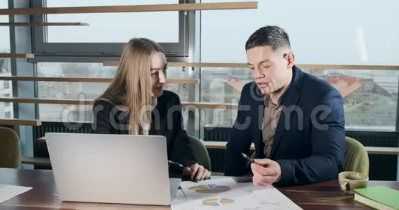 男人和女人在灯火通明的现代办公室里讨论工作从事手提电脑工作的有关男性和女性视频的预览图