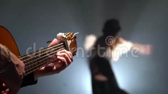 吉他手演奏弗拉门戈女孩跳舞从后面的光烟雾黑背景视频的预览图