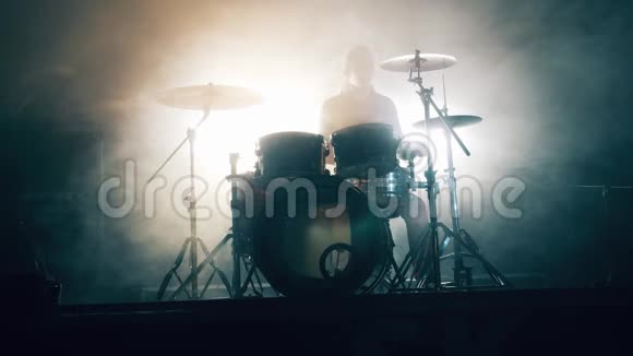 一个男人正在一个黑暗的工作室里用白烟打鼓鼓组鼓包在黑暗中鼓手演奏音乐会视频的预览图