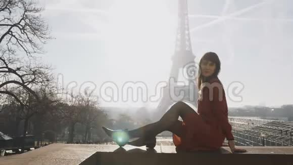 美丽快乐的白种人女人穿着红色的裙子坐着在史诗般的日出巴黎埃菲尔铁塔天景慢动作视频的预览图