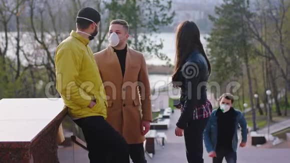 一群有魅力的朋友在公园里开会他们一边聊天一边戴着冠状病毒的防护面具视频的预览图