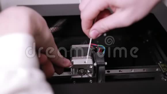3D技术两个人的手把一根塑料白线插进打印机的尖头视频的预览图