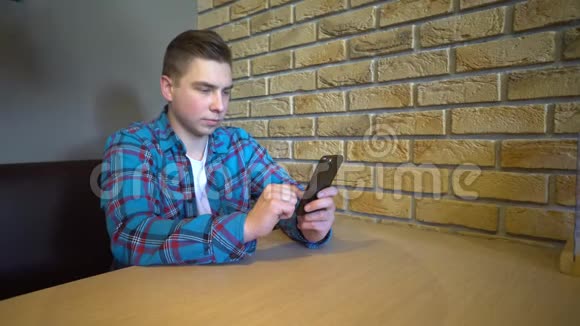 一个带电话的年轻人坐在桌子旁一个男人坐在家里的一张桌子上手里拿着一部电话视频的预览图