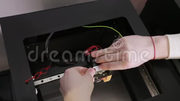 3D技术两个人用手把塑料灰线塞进打印机的针中视频的预览图