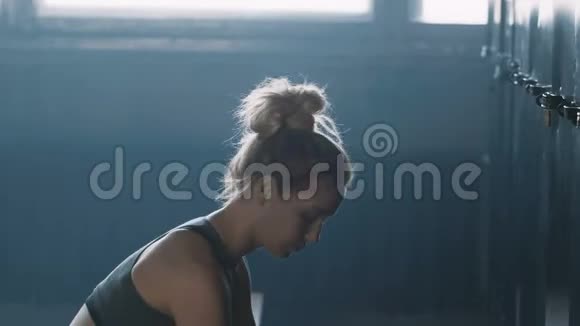 年轻漂亮的金发女郎独自一人在黑暗的健身房更衣室里在比赛前感到失落和压力视频的预览图