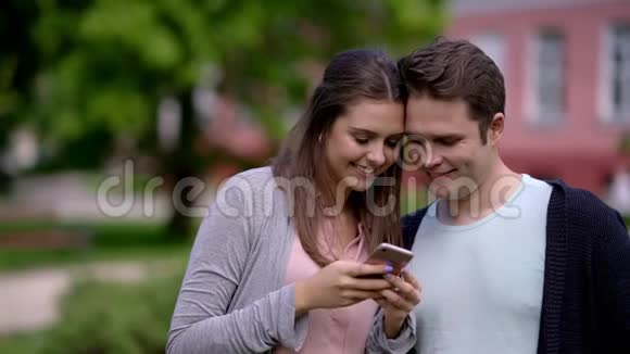 快乐的一对夫妇花时间在户外使用智能手机视频的预览图