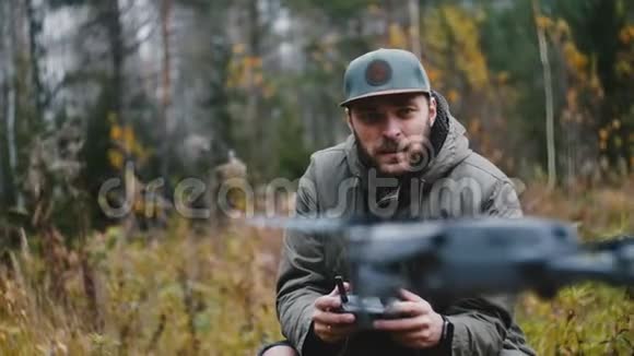 年轻的快乐休闲白种人摄影师男子正在控制无人机相机飞机与遥远的秋天森林视频的预览图