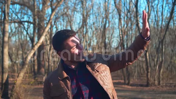 春天公园背景上穿皮夹克的人的肖像一个微笑的人喜欢即将到来的春天看上去视频的预览图