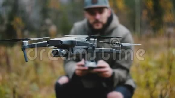 近距离无人机摄像机飞机转向由年轻快乐的高加索摄影师男子控制在秋天的森林视频的预览图