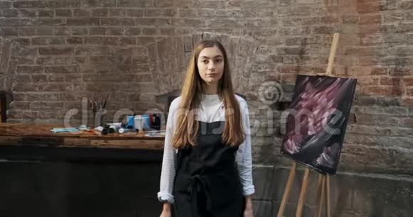 有才华的漂亮女艺术家的肖像与画笔和她的背景画布当代年轻女画家视频的预览图