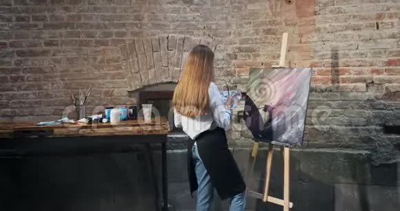 背面的观点有才华的创新漂亮的女艺术家画与画笔在画布上当代年轻女性视频的预览图