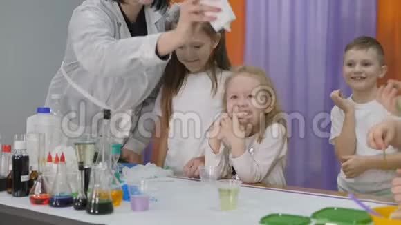 儿童化学实验女人把一种绿色的物质倒进一个透明的玻璃里孩子们很惊讶女孩是视频的预览图