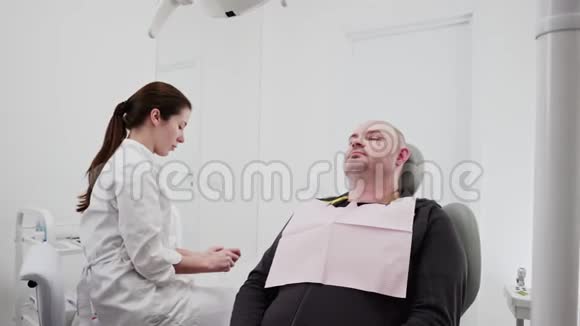 女牙医使用消毒设备进行检查和手术坐在牙科手术椅上的男病人视频的预览图