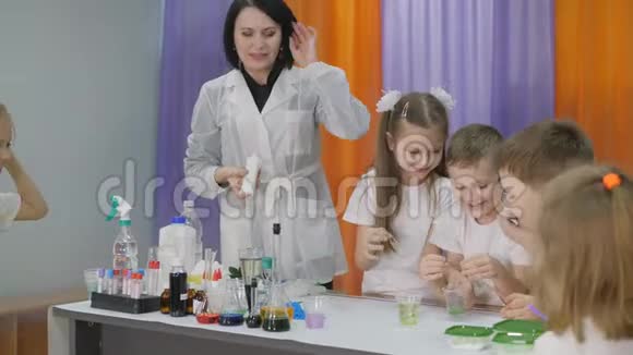 儿童化学实验女人把一种绿色的物质倒进一个透明的玻璃里孩子们很惊讶那个男孩视频的预览图
