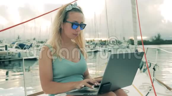 年轻女子在游艇上工作时用笔记本电脑打字视频的预览图