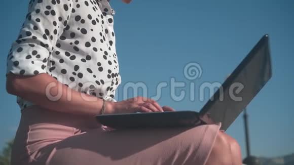 白人商务女性穿着白色衬衫带着豆坐在街上的长凳上在笔记本电脑后面工作视频的预览图