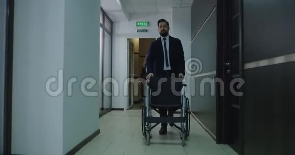 在办公室走廊里推空轮椅的商人视频的预览图