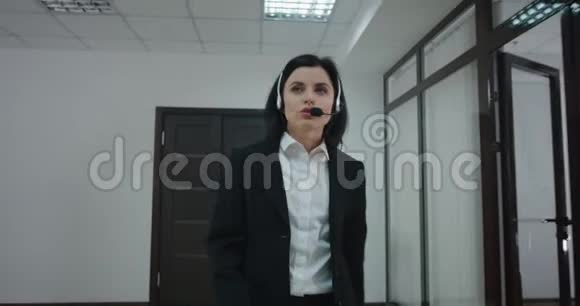 女商人在办公室走廊用耳机打电话视频的预览图