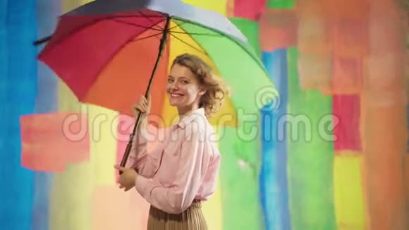 开朗的白种人年轻女子带着彩虹伞在彩色演播室的背景下玩得很开心积极向上的青年视频的预览图