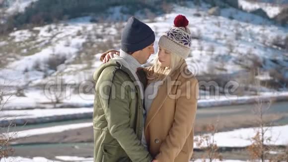 年轻夫妇抱着美丽的雪山在背景上视频的预览图