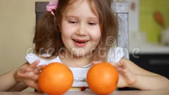 在孩子的手里合上橙色小女孩在玩两个橘子健康食品水果中的维生素维生素C视频的预览图