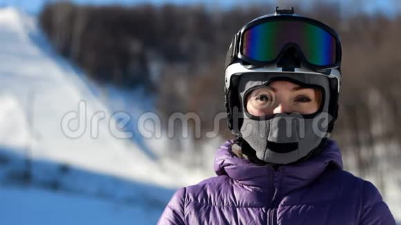 戴着头盔戴着面罩的女人戴上墨镜准备滑雪登山滑雪视频的预览图