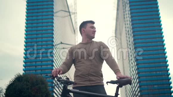 健康的生活方式观念一个戴着耳机的年轻人在市中心骑着自行车在户外听音乐视频的预览图