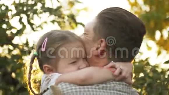 父亲手里拿着小女孩在户外拥抱的肖像爸爸咕哝着和他接吻视频的预览图
