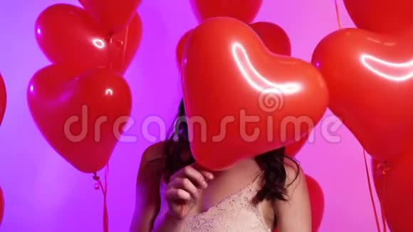 一个年轻快乐的女人把她的脸藏在一个心形的气球后面视频的预览图