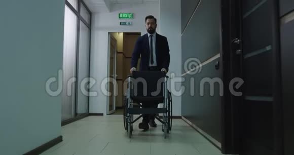 职员推空轮椅办公室走廊视频的预览图