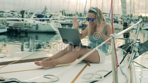 视频聊天视频通话的概念一个女孩坐在游艇上用笔记本电脑打电话视频的预览图