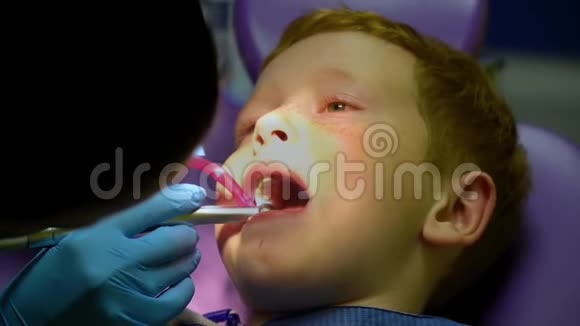坐在牙科椅上的牙医接待处吓坏了的红发男孩在哭儿童牙科视频的预览图
