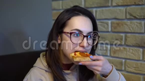 一个年轻的女人正在吃一片比萨饼女人坐在餐馆里吃披萨特写视频的预览图